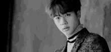a black and white photo of a young man wearing a choker .