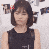 a woman in a black tank top is standing in front of a wall with pictures of women on it .