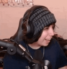 a person wearing a beanie and headphones is sitting in front of a microphone .
