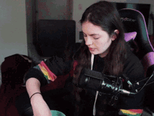 a woman wearing a black sweater with rainbow sleeves is sitting in front of a racer chair