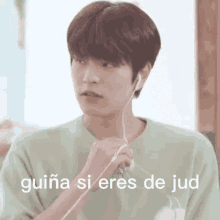 a young man is wearing ear buds and has the words guiana si eres de jud written on the bottom