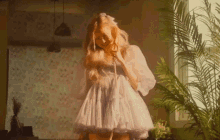 a woman in a white dress is talking on a phone in a room .