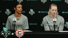 two women wearing new york basketball shirts sit at a table with microphones