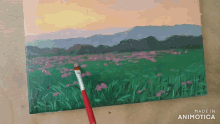 a painting of a field of flowers is being painted with a brush