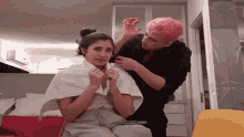 a man with pink hair is getting a woman 's hair done