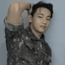 a young man in a military uniform is holding his hair .