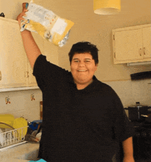 a man in a black shirt is holding a bag of chips in his hand