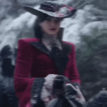 a woman in a red jacket and hat is standing in the snow .