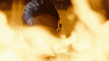 a man 's head is visible through a hole in a wall with flames coming out of it .