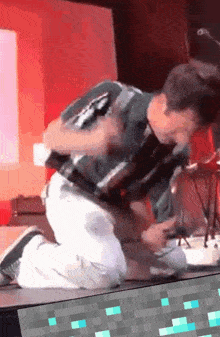 a man is kneeling down on a stage in front of a computer monitor
