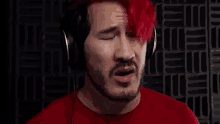 a man with red hair and a beard is wearing headphones and making a funny face .
