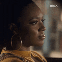 a woman wearing hoop earrings is sitting in a car with the word max on the bottom right