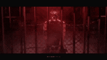 a man is chained to a fence in a dark room with a red background