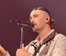 a man singing into a microphone with a guitar strap around his neck