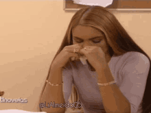 a woman with long hair is sitting at a table holding her nose .