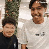 a man wearing a white t-shirt that says hello smiles next to another man