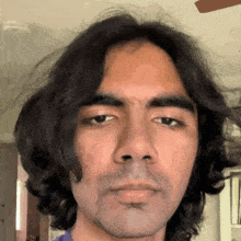 a close up of a man 's face with a ceiling fan behind him