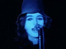 a woman singing into a microphone with a blue hat on