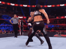 two women are wrestling in a ring with a referee and the word raw behind them