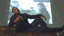 a man is laying on a couch in front of a projector screen that says " the maw "