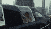 a man is sitting in the back seat of a car looking out the window