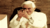 a man in a white robe with a cross around his neck is smiling