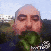 a man is eating a piece of broccoli with the free content network logo behind him