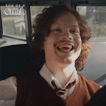a man with curly hair and a mustache is laughing on a school bus ..