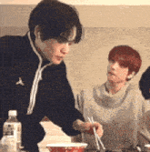 a group of people are sitting at a table eating food from bowls .