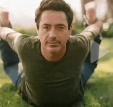 a man is laying on the grass with his arms outstretched and his legs crossed .