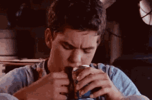 a man is drinking a can of pepsi while sitting down .
