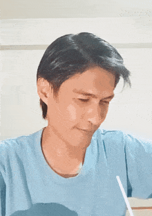a man in a light blue shirt is looking down at something