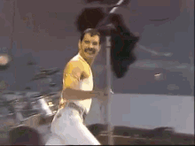 a man with a mustache is standing on a stage in front of a drum set