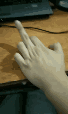 a person 's hand is pointing at a laptop computer