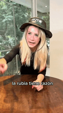 a woman sitting at a table wearing a hat that says cayo