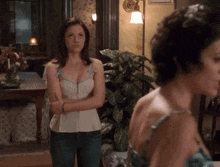 a woman in a white top and jeans stands next to another woman