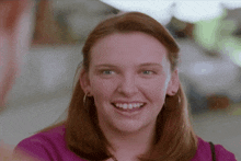 a woman in a purple shirt is smiling with her teeth showing