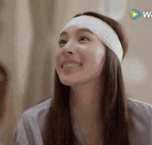 a woman wearing a headband is smiling in front of a sign that says we