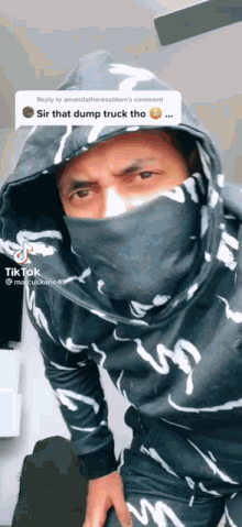 a man wearing a black and white hoodie with a face mask on his face .