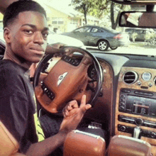 a young man is sitting in a bentley car giving a peace sign