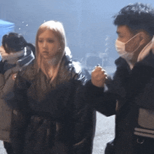 a man wearing a mask is talking to a woman