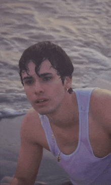 a man in a tank top is splashed by a wave in the ocean