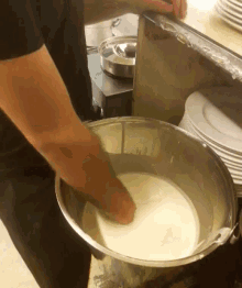 a person is mixing something in a large metal bowl