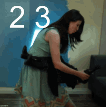 a woman in a blue dress is holding a black cat in front of a blue wall with the number 23 on it