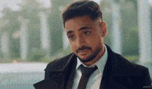 a man with a beard wearing a suit and tie looks at the camera .