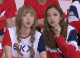 a couple of girls are sitting next to each other in a stadium .