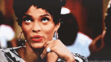 a woman wearing hoop earrings and a ring on her finger is looking up .