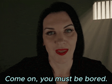 a woman in a dark room with the words come on you must be bored