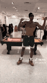 a shirtless man is standing in front of a pool table in a store