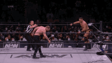two men are wrestling in a wrestling ring with a referee .